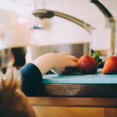 Child reaching for strawberries